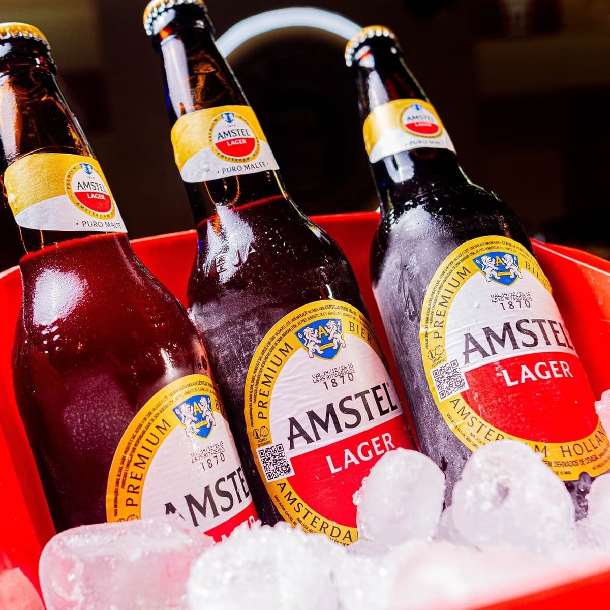 Três cervejas long neck geladas dentro de um balde com gelo