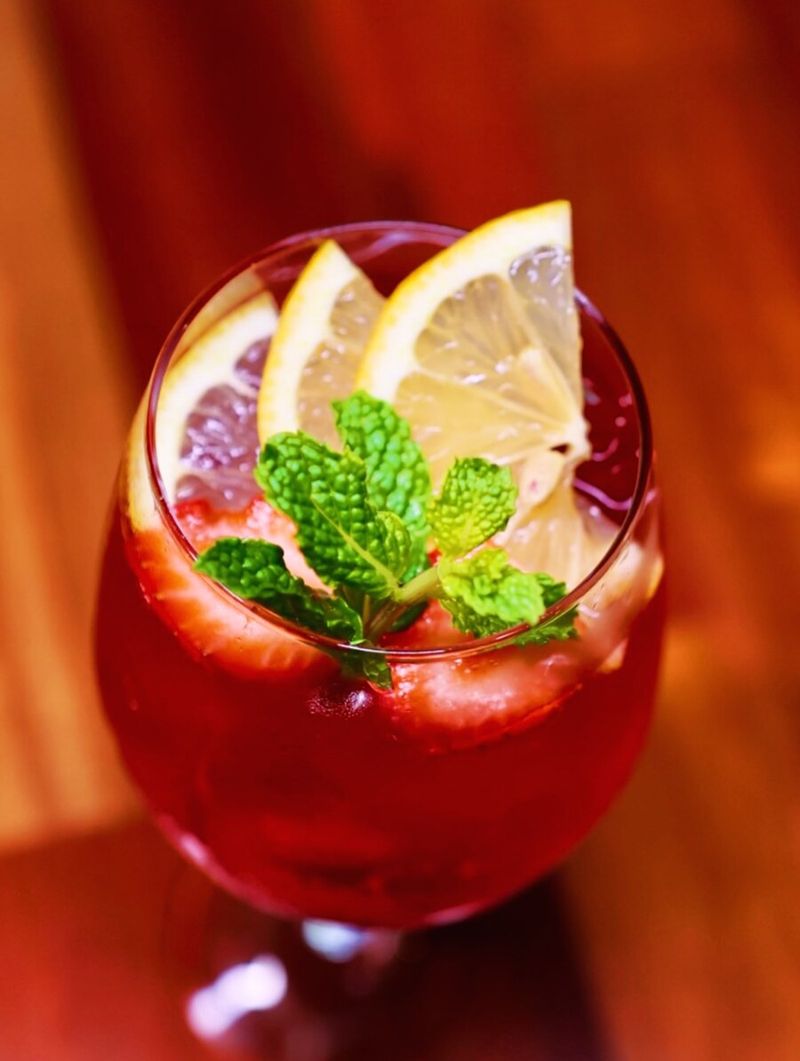 Drink autoral vermelho com frutas vermelhas, hortelã e rodelas de limão
